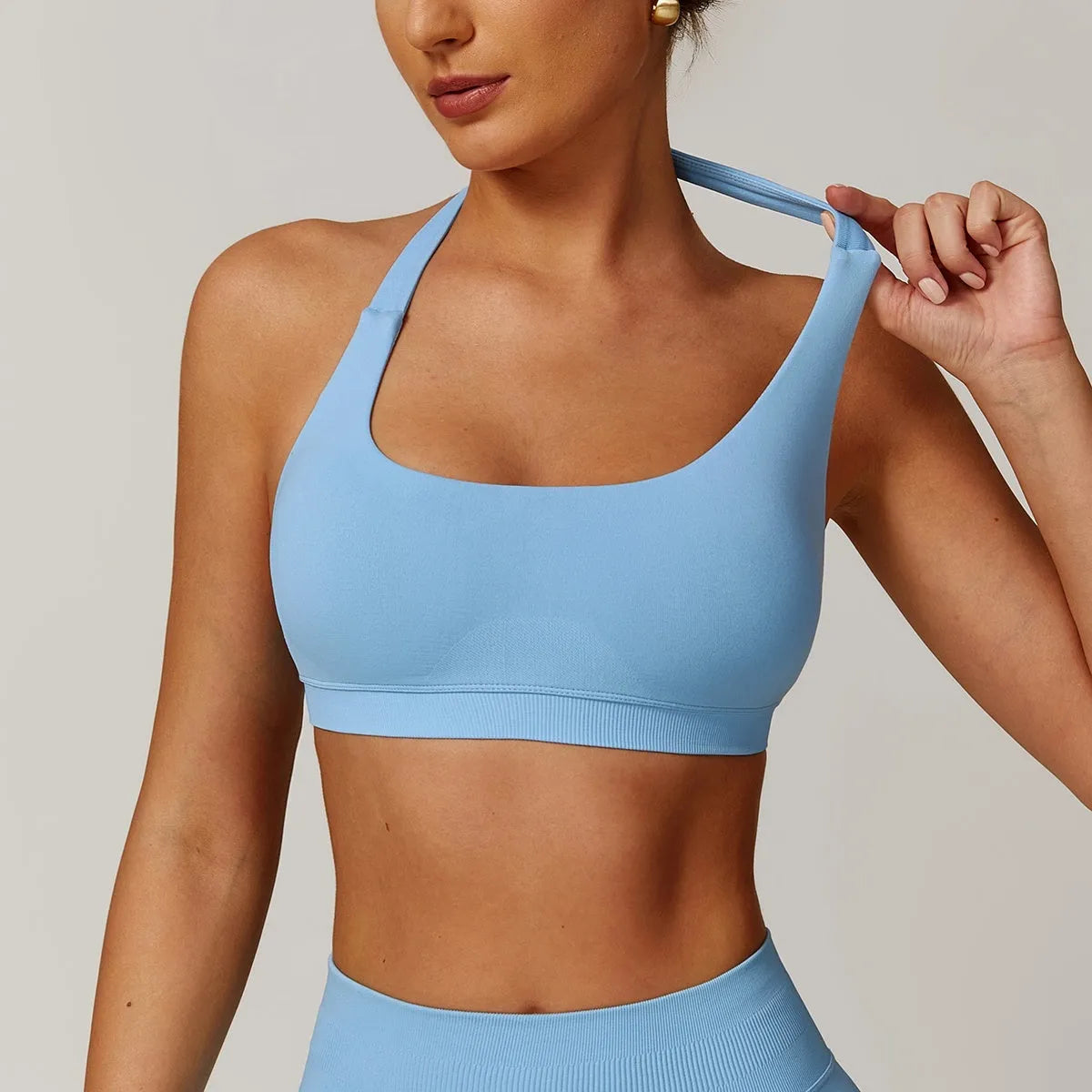 Women's halter-style sports bra in multiple colours, showing hollow back design and removable pads.