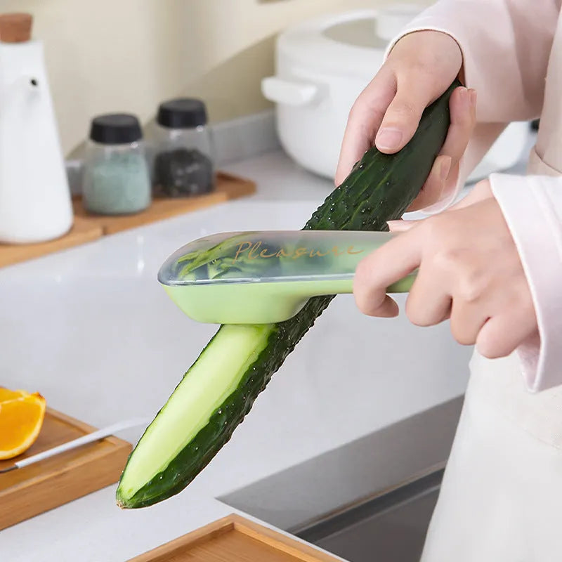 Dark green vegetable peeler with storage tube, showing stainless steel blade and hanging hole on handle.