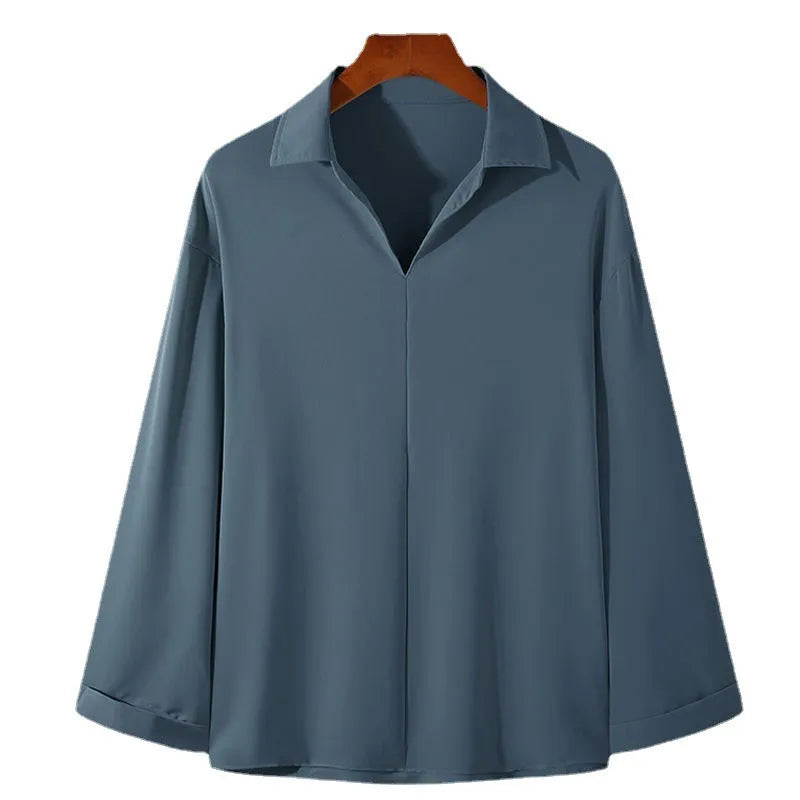 Man wearing a loose fit light business casual shirt in blue, showing lapels and long sleeves.