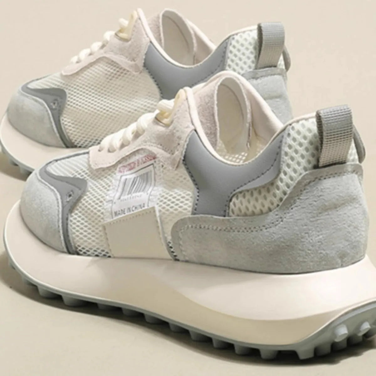 Grey and pink women's low-top retro sneakers with round toe and shallow mouth on a rubber sole.