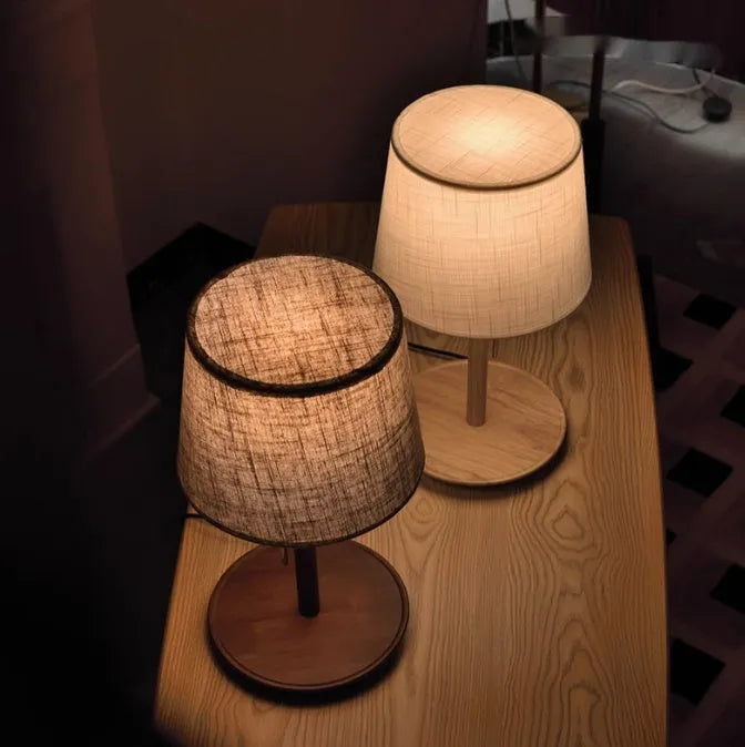 Walnut coloured solid wood table lamp with white cloth lampshade and black cable switch.