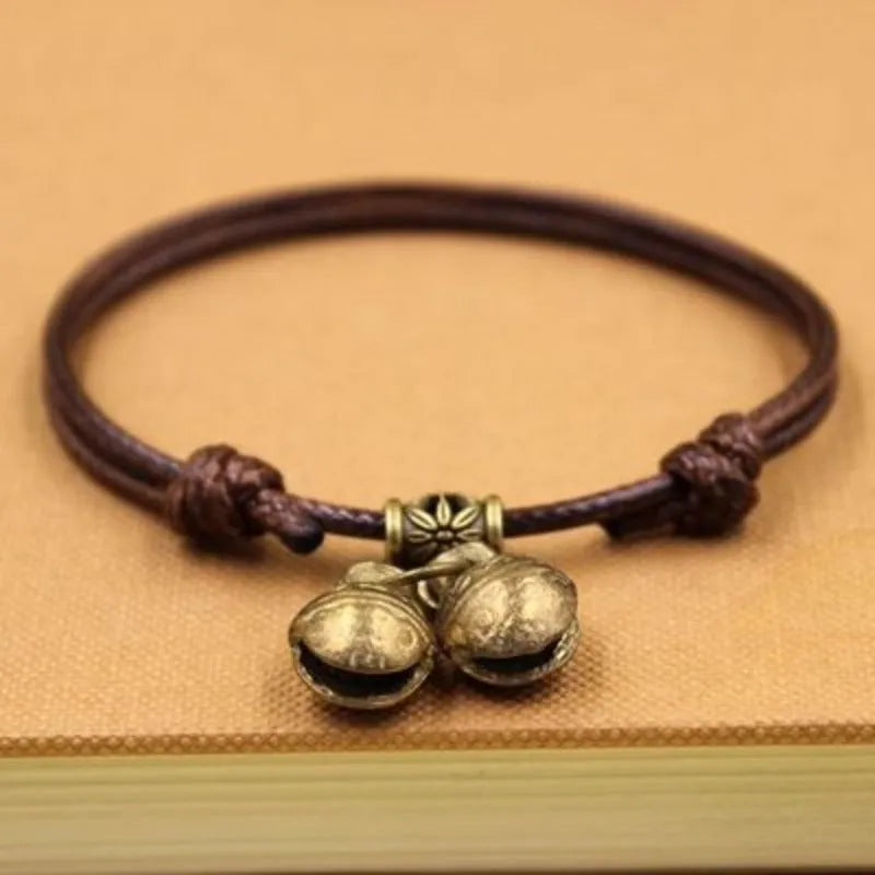 Small dog wearing adjustable nylon rope collar with brass bell in black, red, or coffee colour