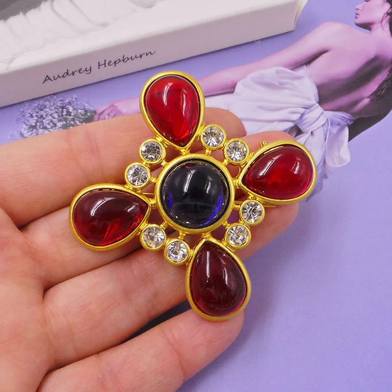 Close-up of a detailed baroque cross brooch with crystal accents on a zinc alloy base.