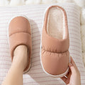 Pair of down cotton indoor slippers with artificial leather upper and thick rubber sole.