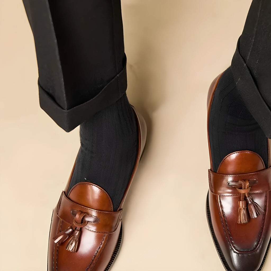 Men's black and brown tassel loafers with polished leather upper and rubber sole in British business casual style