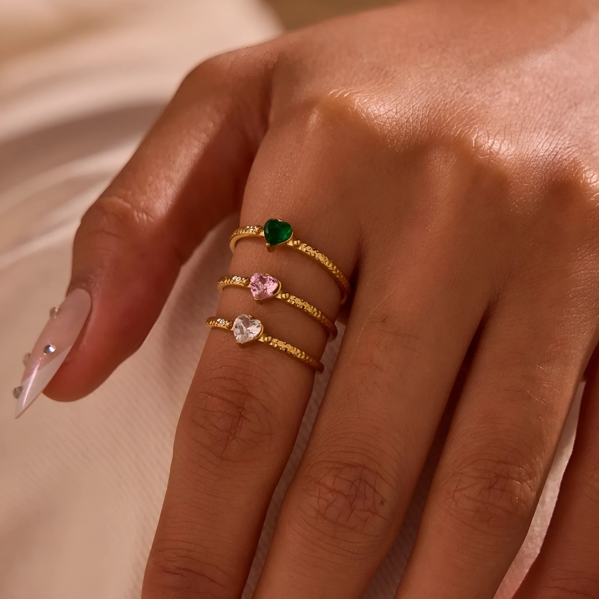 Open ended stainless steel ring with a geometric heart shape and inlaid zircon stone in white, pink, or green.