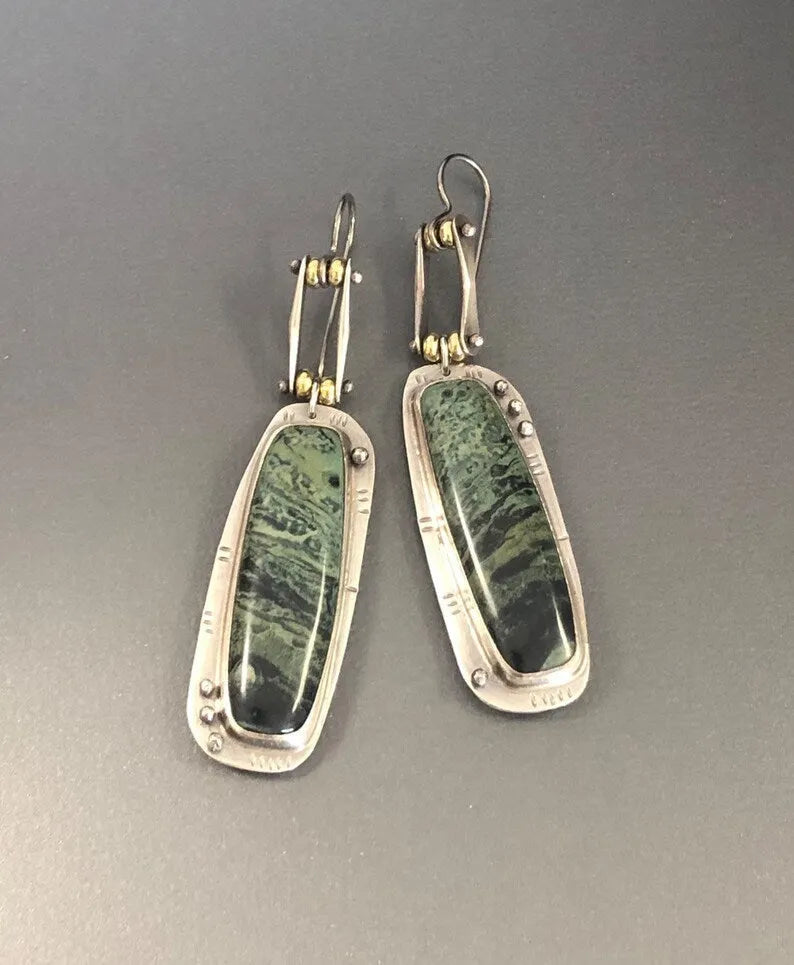 Close-up of women's geometric alloy earrings with a white and grey marble pattern.