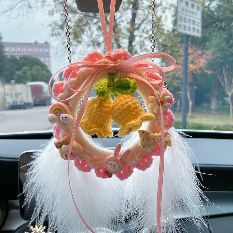 Handwoven wool bell orchid car pendant in green, hanging with dreamcatcher charm.