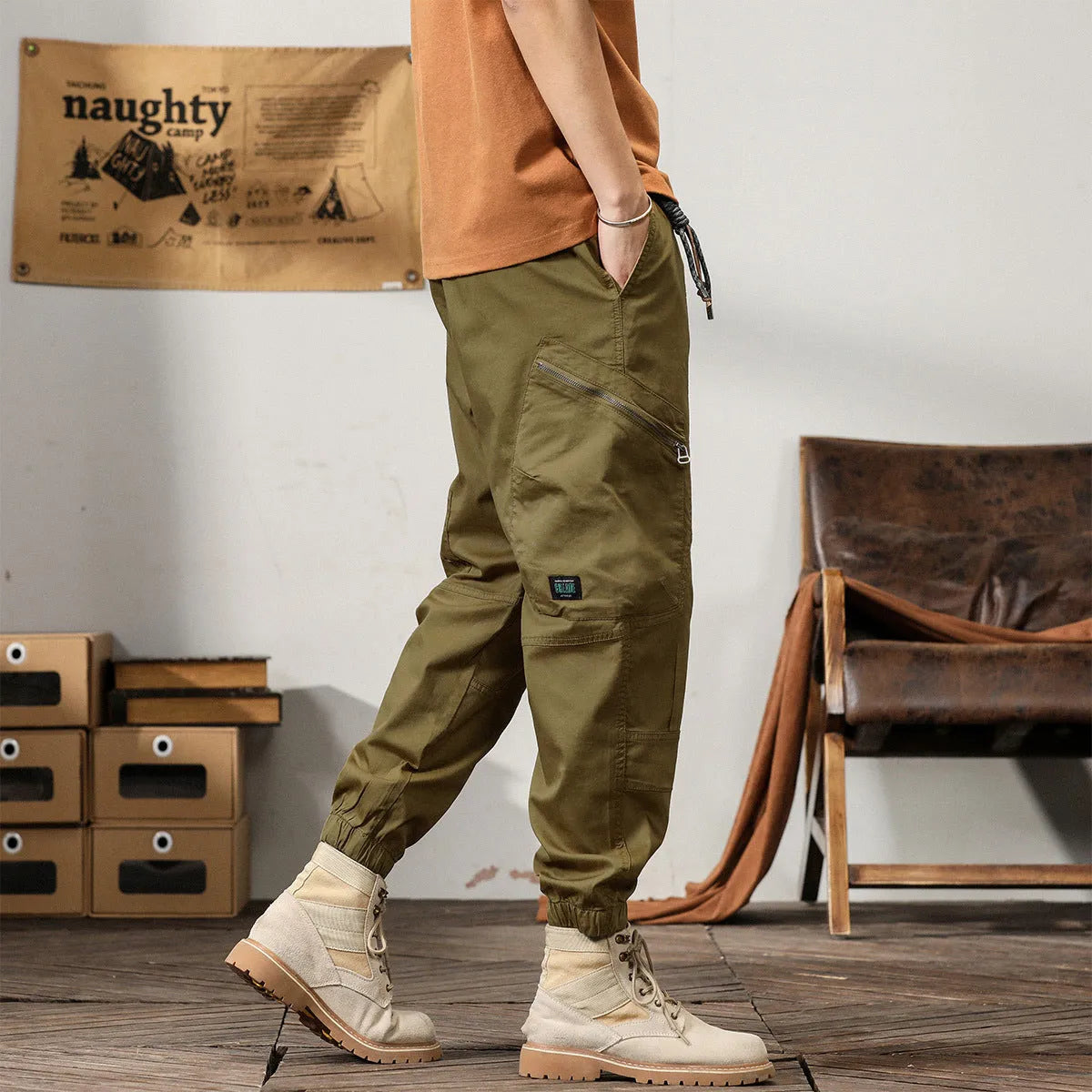 Men's khaki cotton tapered harem pants with ankle bands and a zip fly, laid flat.