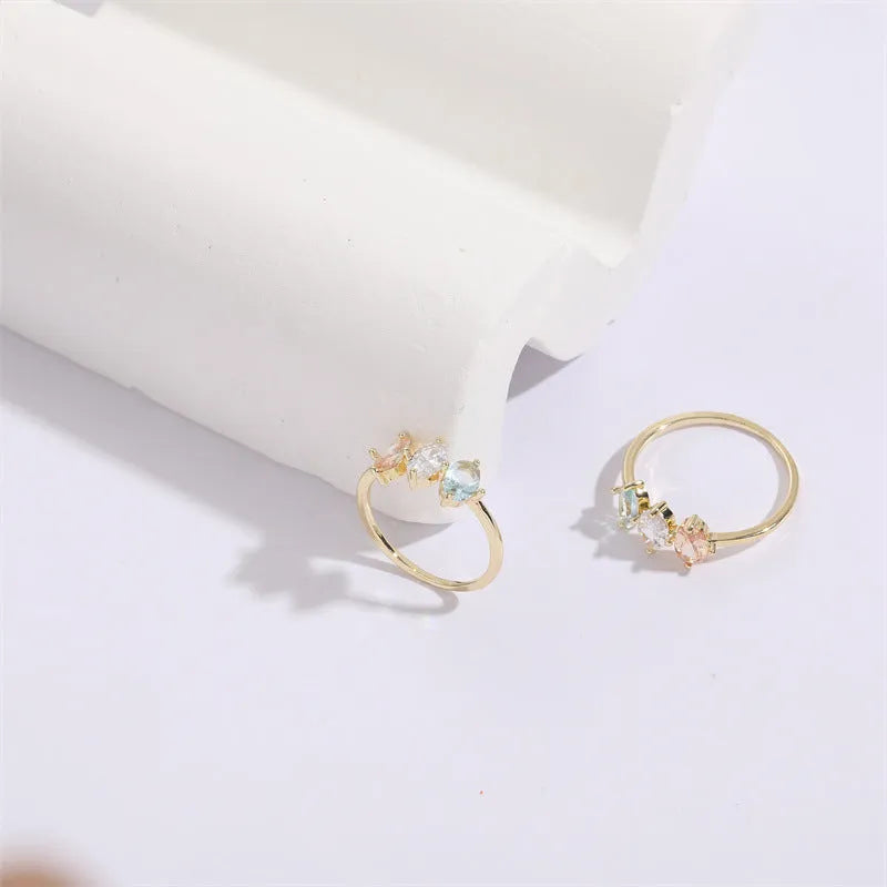 Geometric triangle birthstone ring with horse eye design and tricolour zircon stones on woman's hand