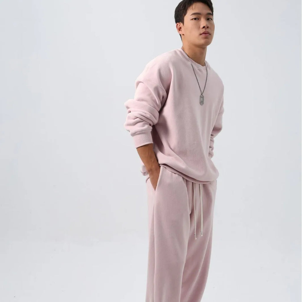 Men's black polar fleece sports suit with loose crew neck jacket and padded trousers on a hanger.