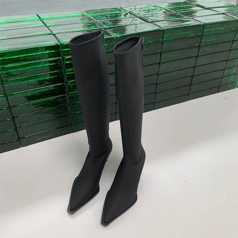 Black pointed toe knee-high boots with a stiletto heel and back zipper, shown on a model
