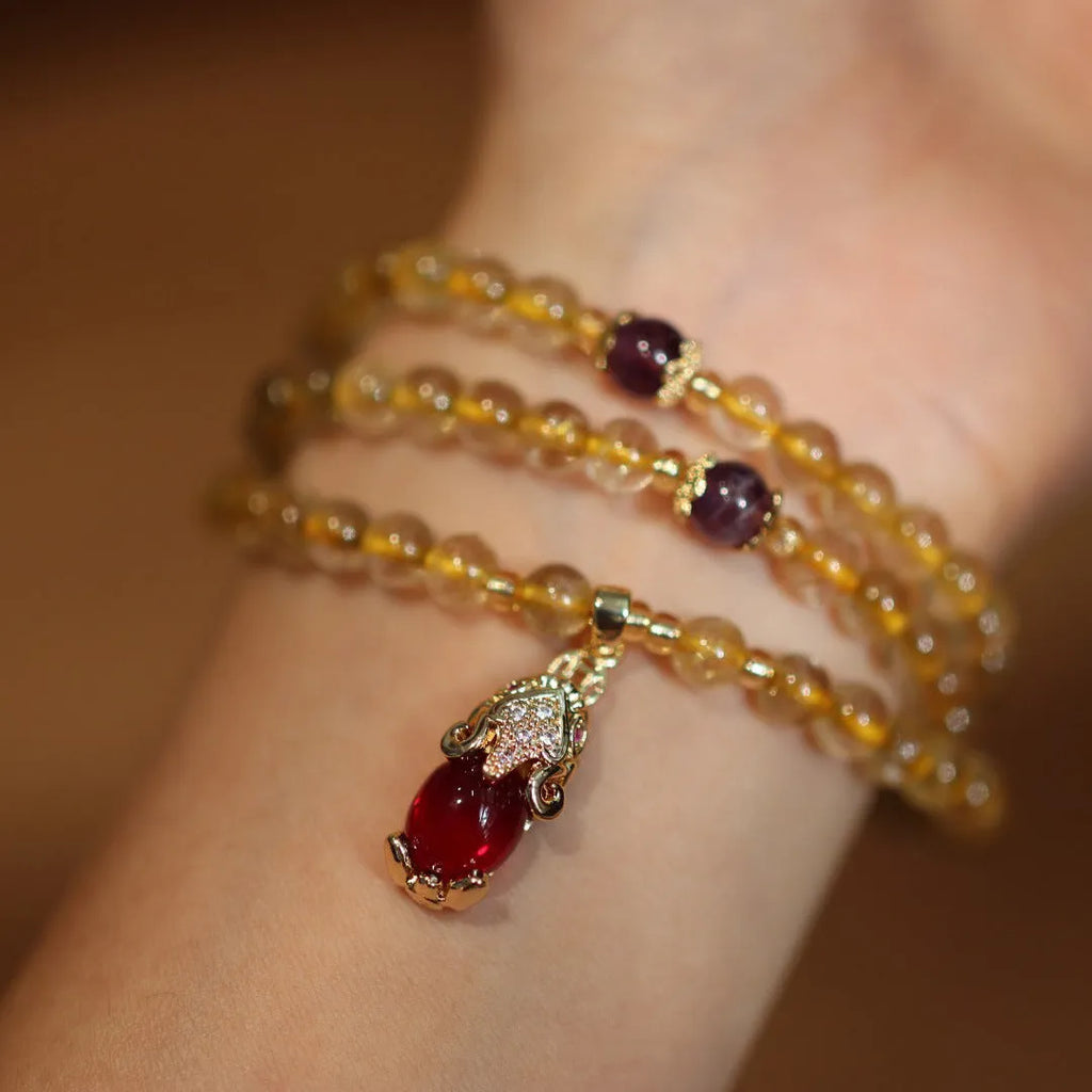 Natural quartz bracelet with three gold-coloured rings and hanging chopstick charms in a Chinese style.
