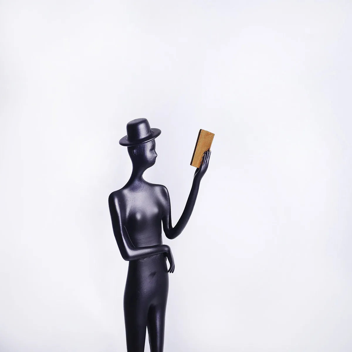 Black aluminium desktop sculpture of a woman reading, modern design.