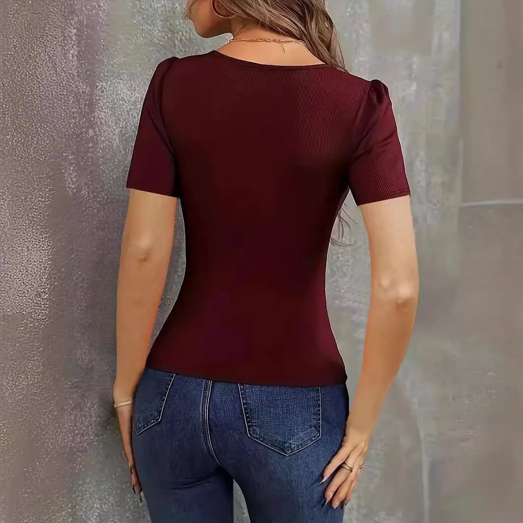 Woman wearing a wine red slim fit knitted short sleeve top with a low neckline.