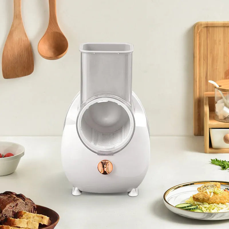 White electric vegetable slicer with rotary grater, three blades, and suction base on kitchen counter