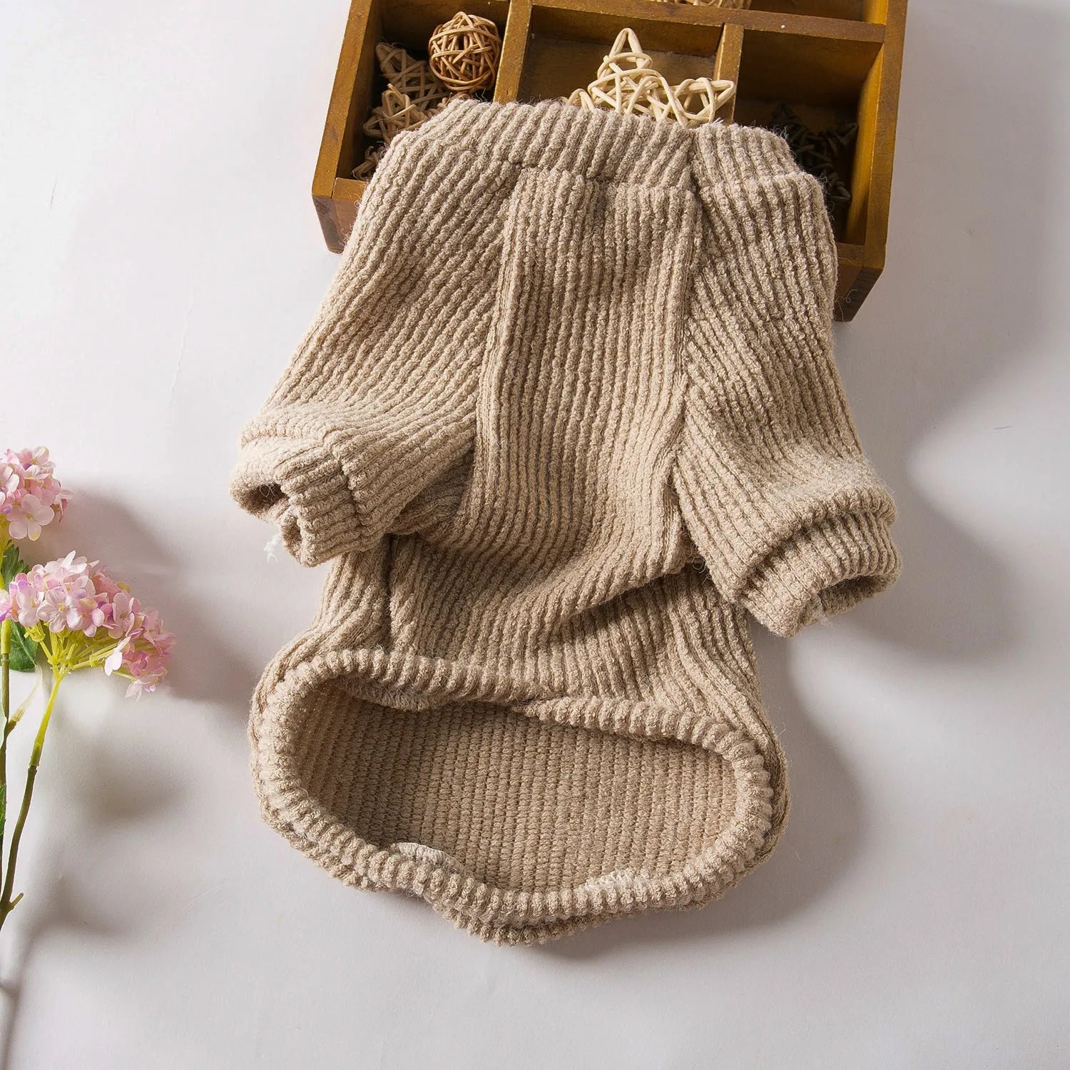Brown knitted pullover sweater on a small dog, showing four-leg design for full coverage.