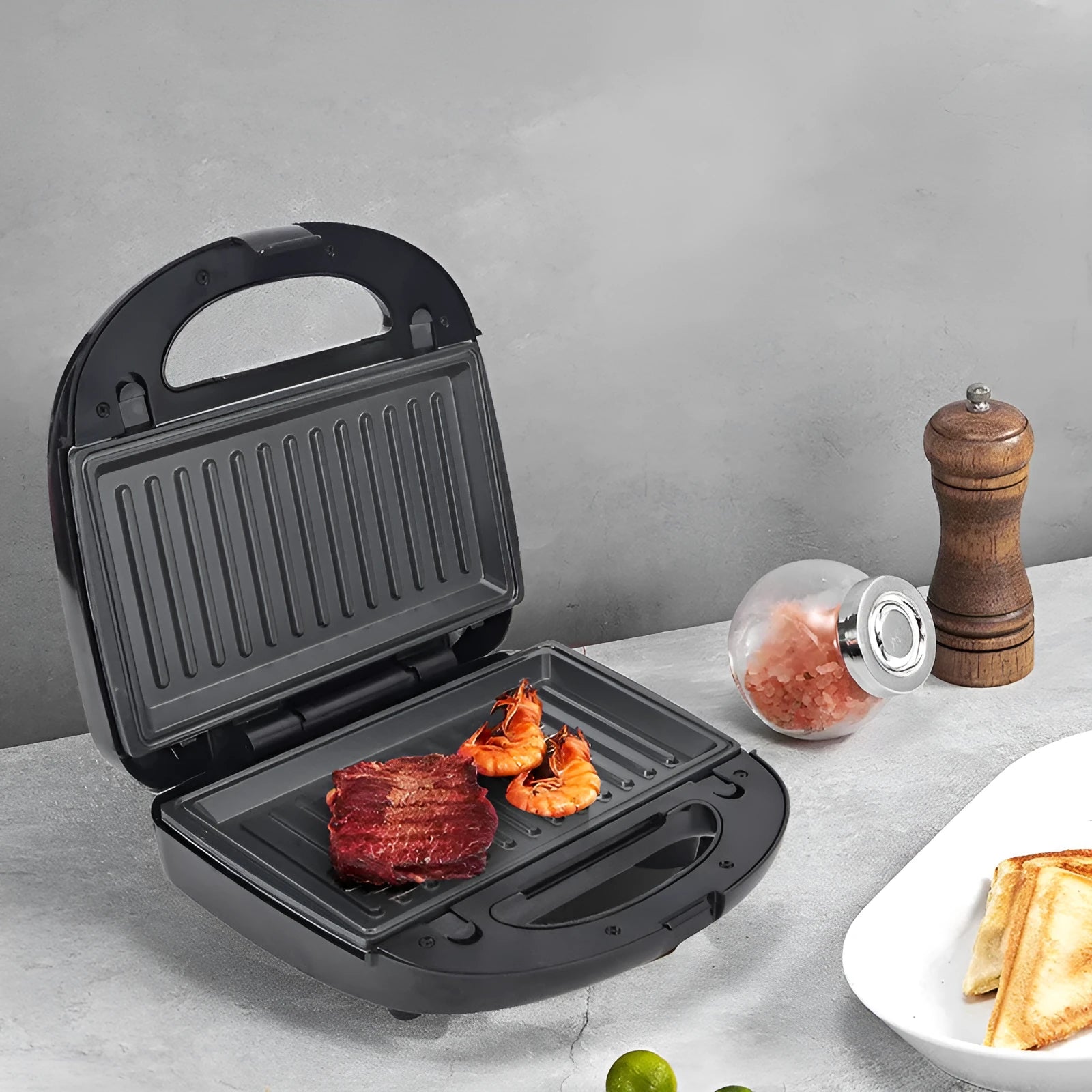 Black electric sandwich toaster with double-sided heating and six non-stick plates on a countertop.