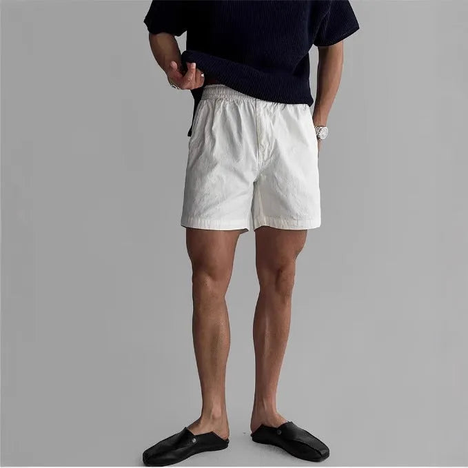 A pair of loose-fitting cotton sports shorts in khaki colour on a white background.