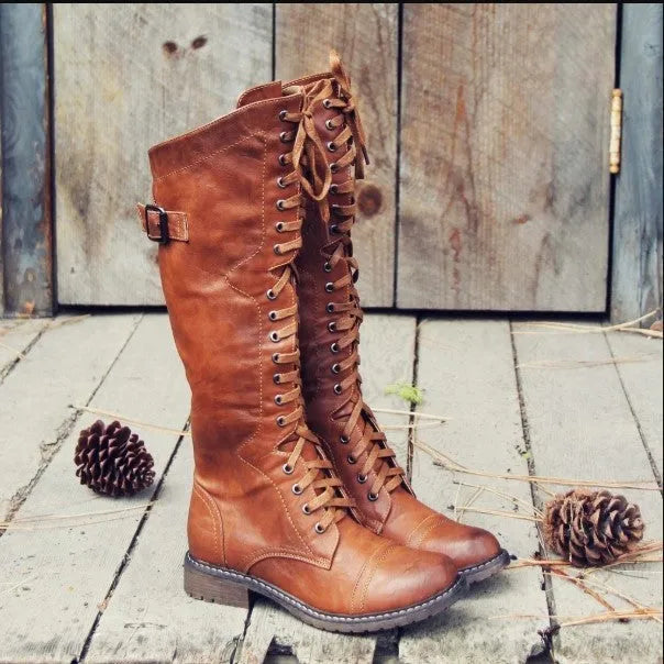 Women's black artificial PU knight boots with cross straps over the ankle.