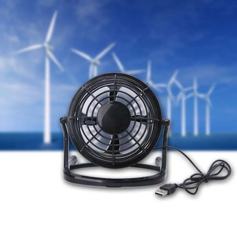 Compact black mini USB desk fan with adjustable tilt, placed next to a laptop.
