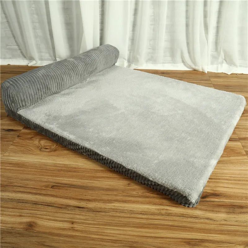 Grey corduroy dog sofa bed with raised sides on a wooden floor, showing its non-slip base.