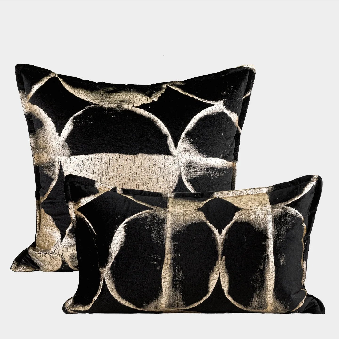 Black and gold abstract pattern decorative cushion with removable cover on a grey sofa.