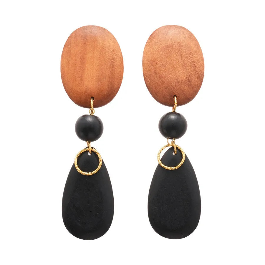 Handcrafted brown and black wooden elliptical earrings with silver needle detail on a retro style background.