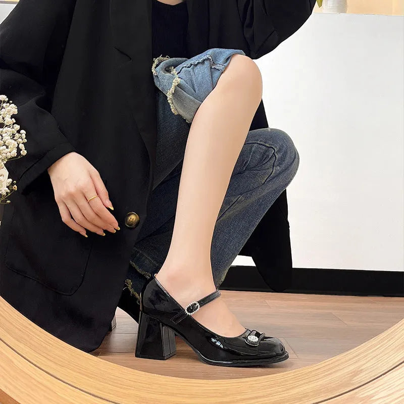 Women's black patent leather round toe shoes with a chunky heel and buckle fastening, shown in a widened fit style.