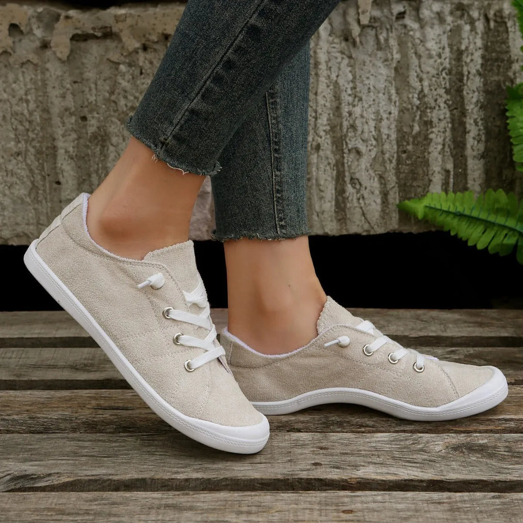 Women's creamy white low-top fabric sneakers with a casual design and rubber sole.