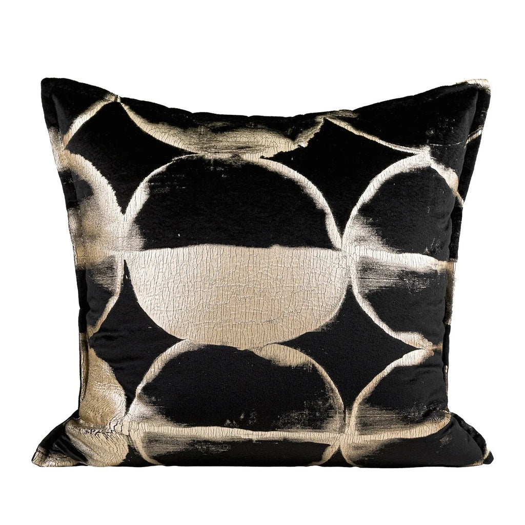 Black and gold abstract pattern decorative cushion with removable cover on a grey sofa.