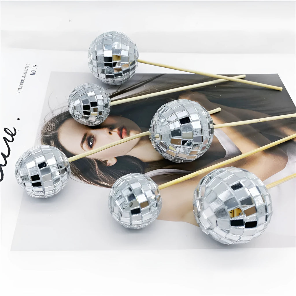 Glass disco ball cake decorations with wooden sticks in multiple sizes on birthday cake