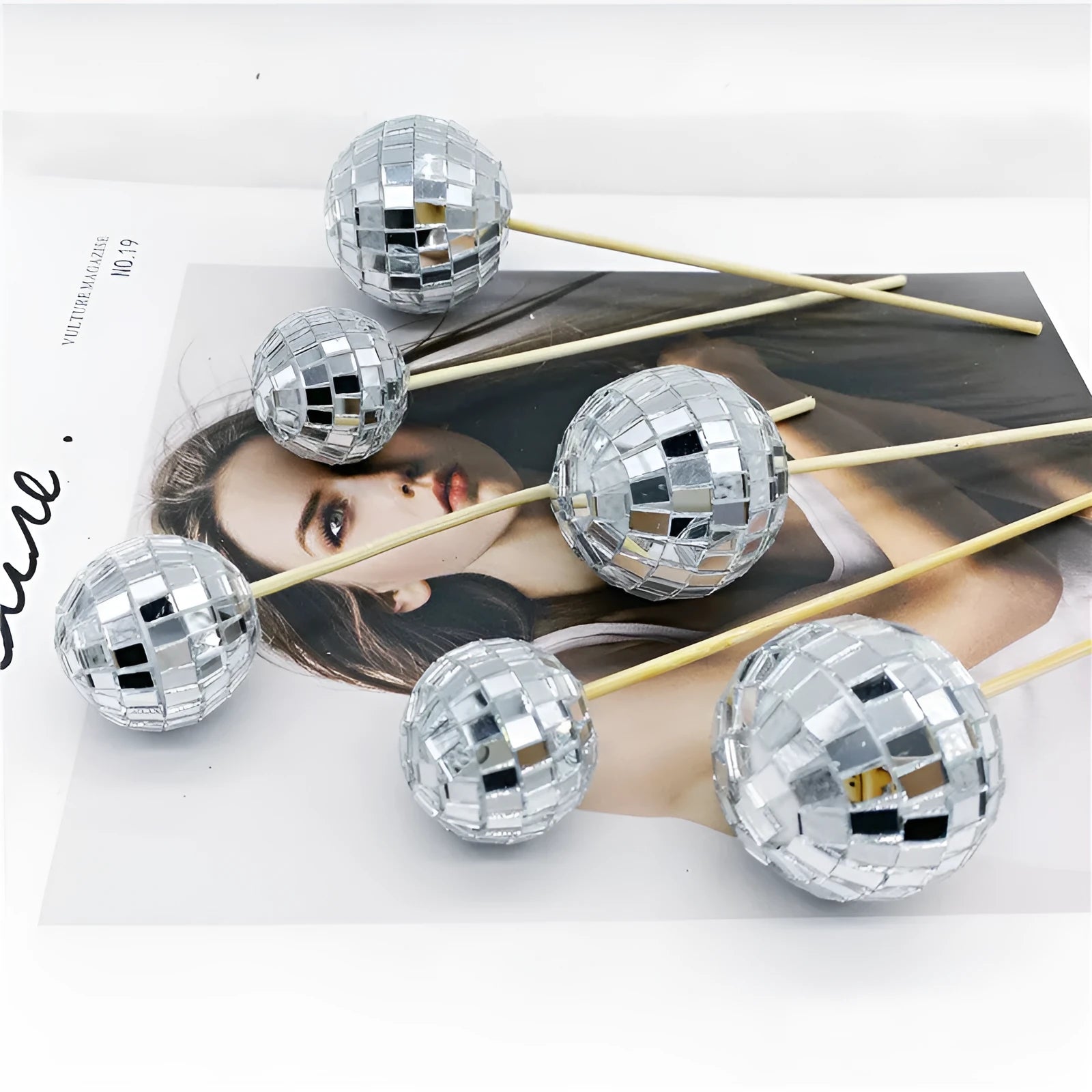Glass disco ball cake decorations with wooden sticks in multiple sizes on birthday cake