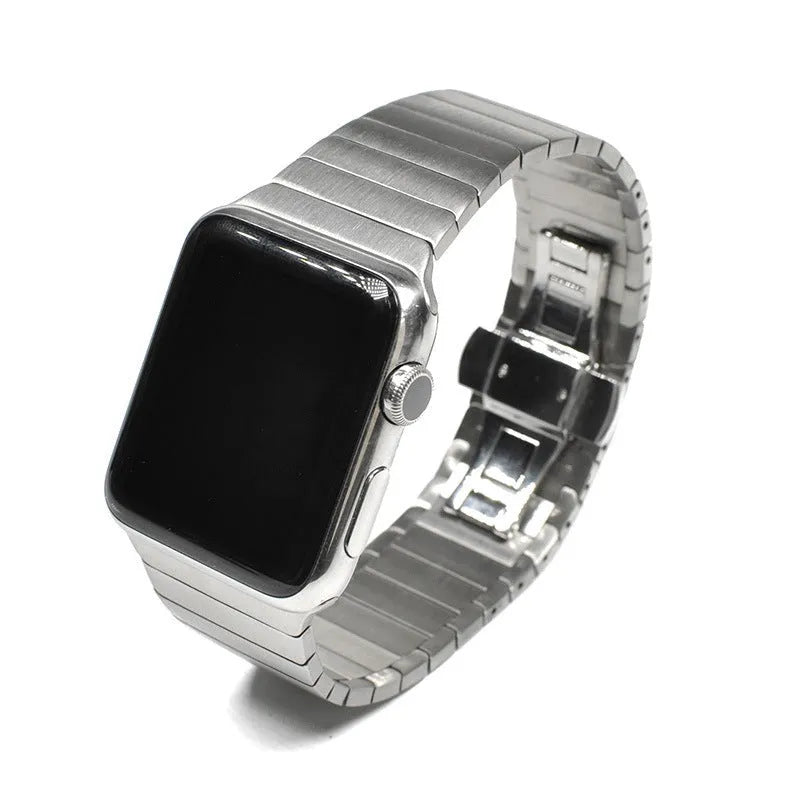 Silver metal Apple Watch strap with butterfly buckle on a wrist, showing the clasp closed.