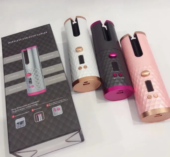 White portable automatic curling iron with a gold ceramic barrel and USB charging cable on a pink background.