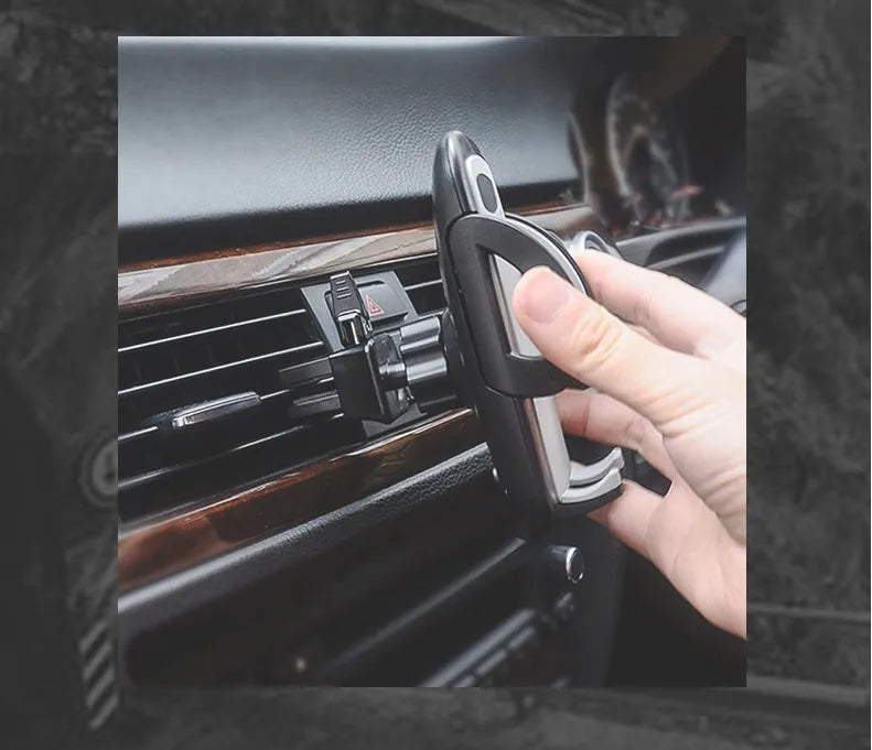 Black plastic car air vent phone holder mounted on car dashboard with mobile phone securely in cradle