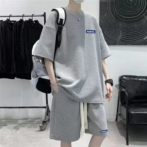 Man wearing a grey waffle-textured cotton leisure sports suit with short sleeves and shorts.