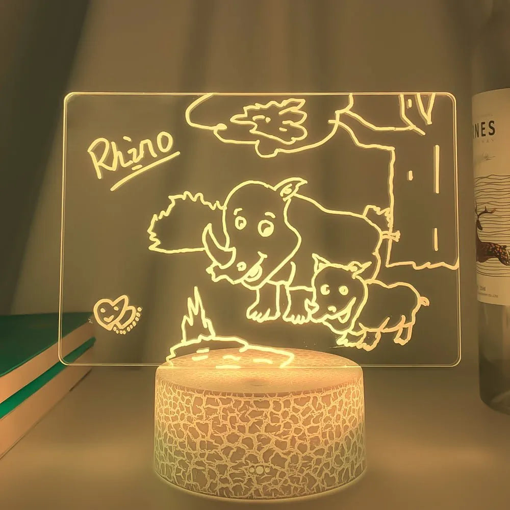 Black 3D acrylic message board LED light with remote control and marker pen on a desk.