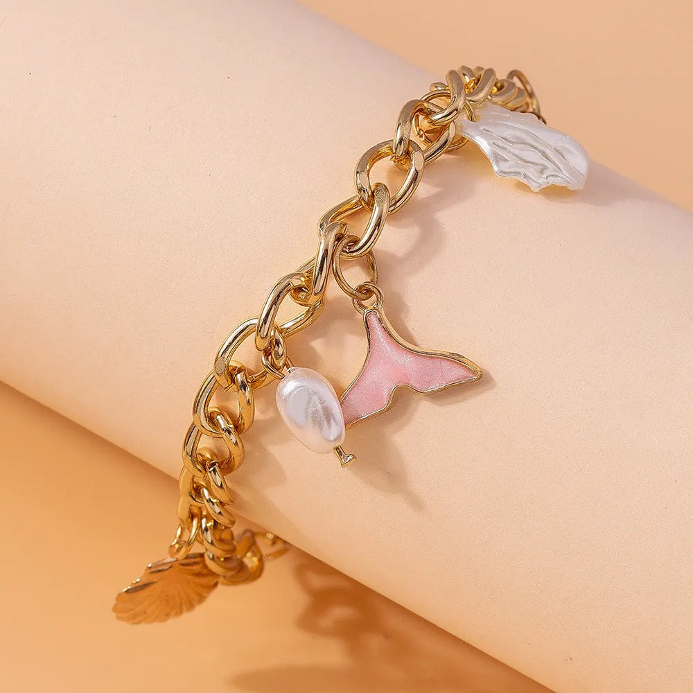Women's white pearl alloy shell pearl mermaid tail bracelet on neutral background