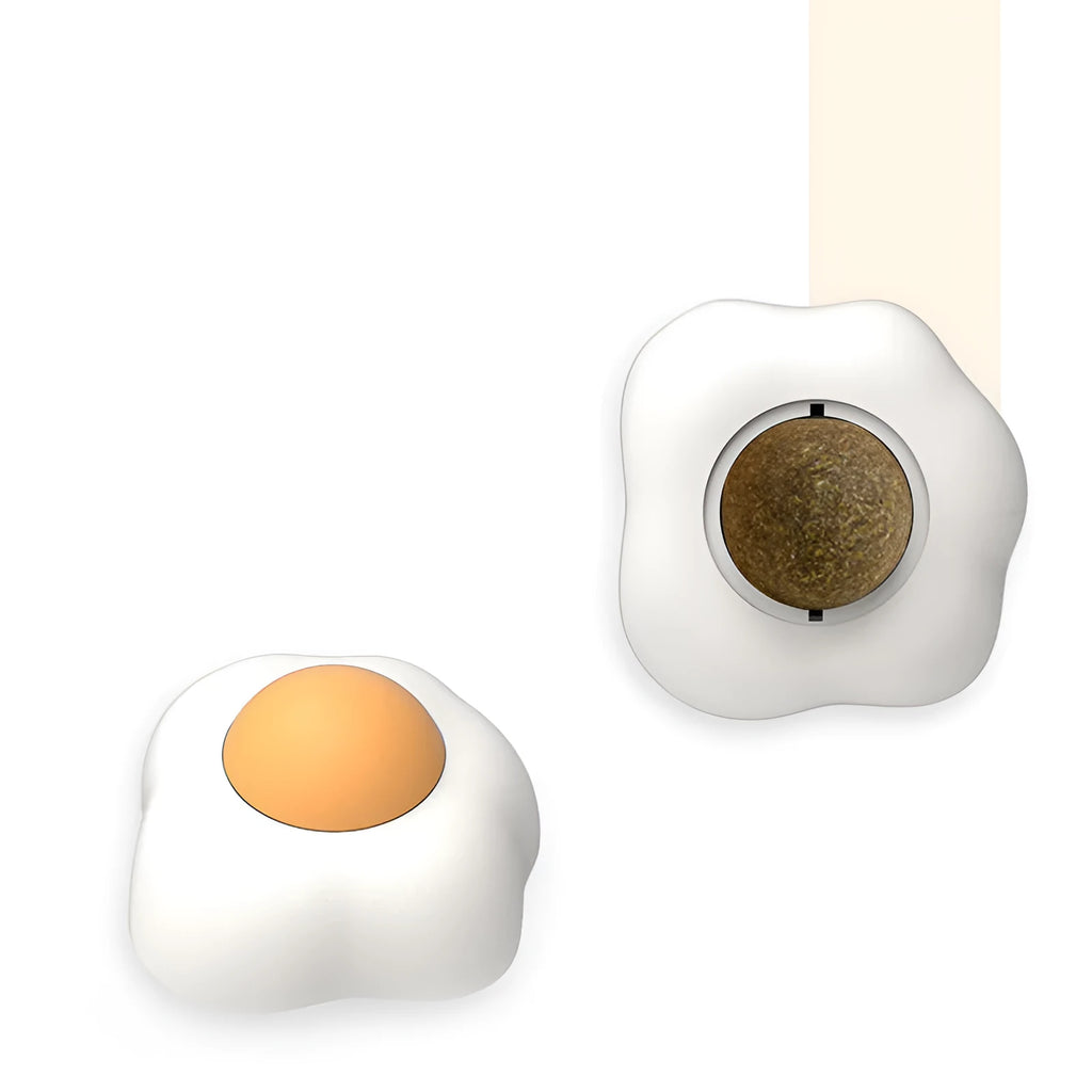 Soft plush catnip ball toy in fried egg shape stuck to a wall, with a cat playing.