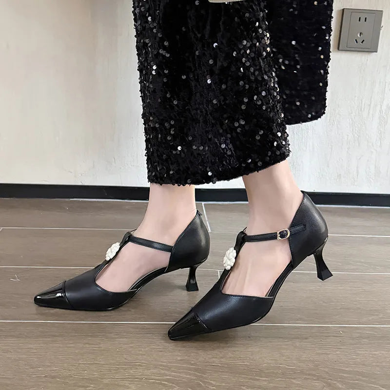 Women's black stiletto heel shoes with pointed toe, flower decoration, and buckle detail on sheepskin upper