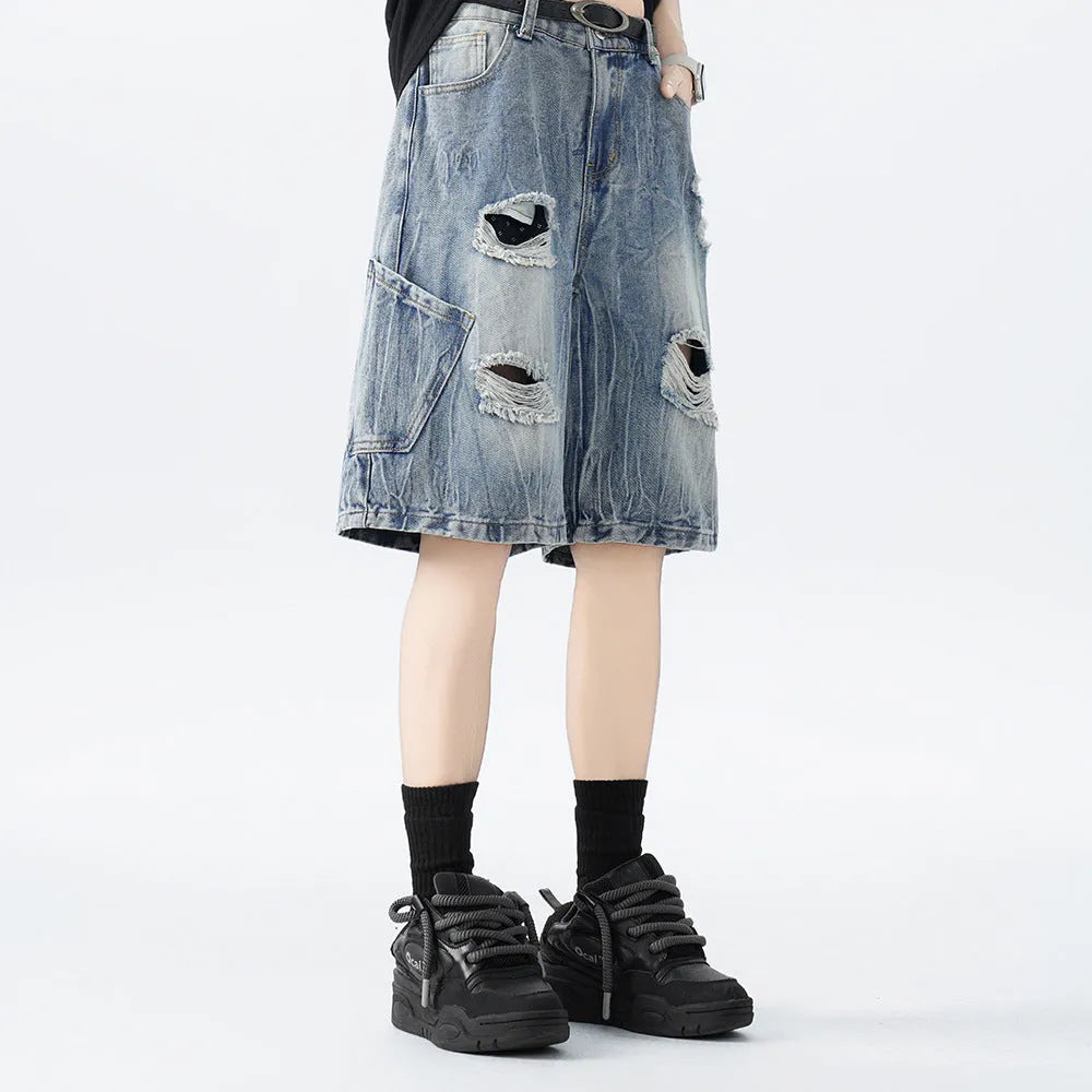 Washed black denim shorts with ripped details and loose retro fit showing front view