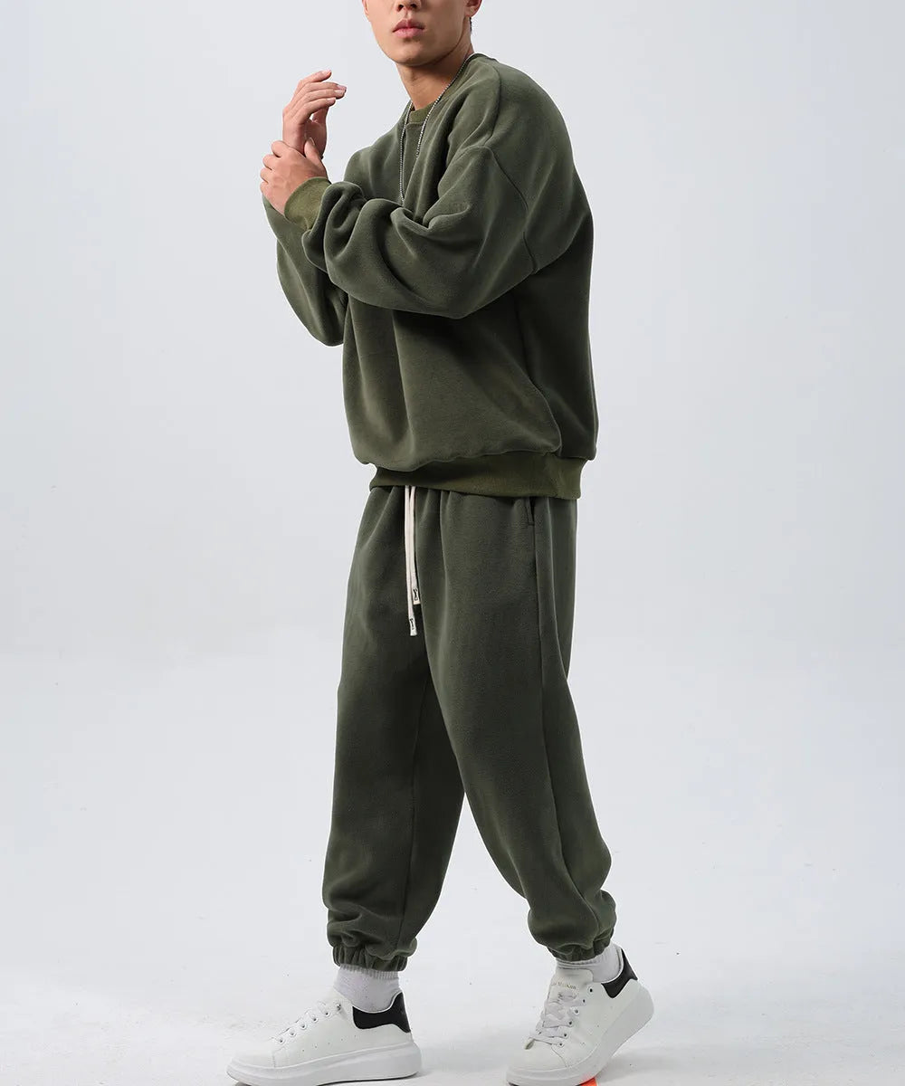 Men's black polar fleece sports suit with loose crew neck jacket and padded trousers on a hanger.