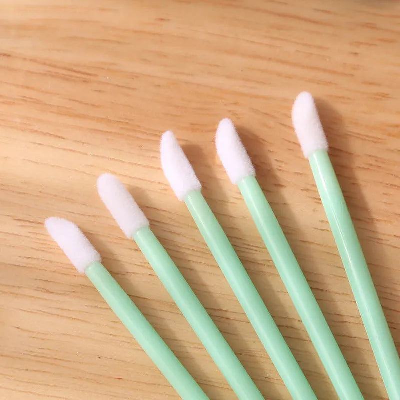 Pack of disposable lip brush applicators with flocked heads and black handles on a white background.