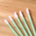 Pack of disposable lip brush applicators with flocked heads and black handles on a white background.