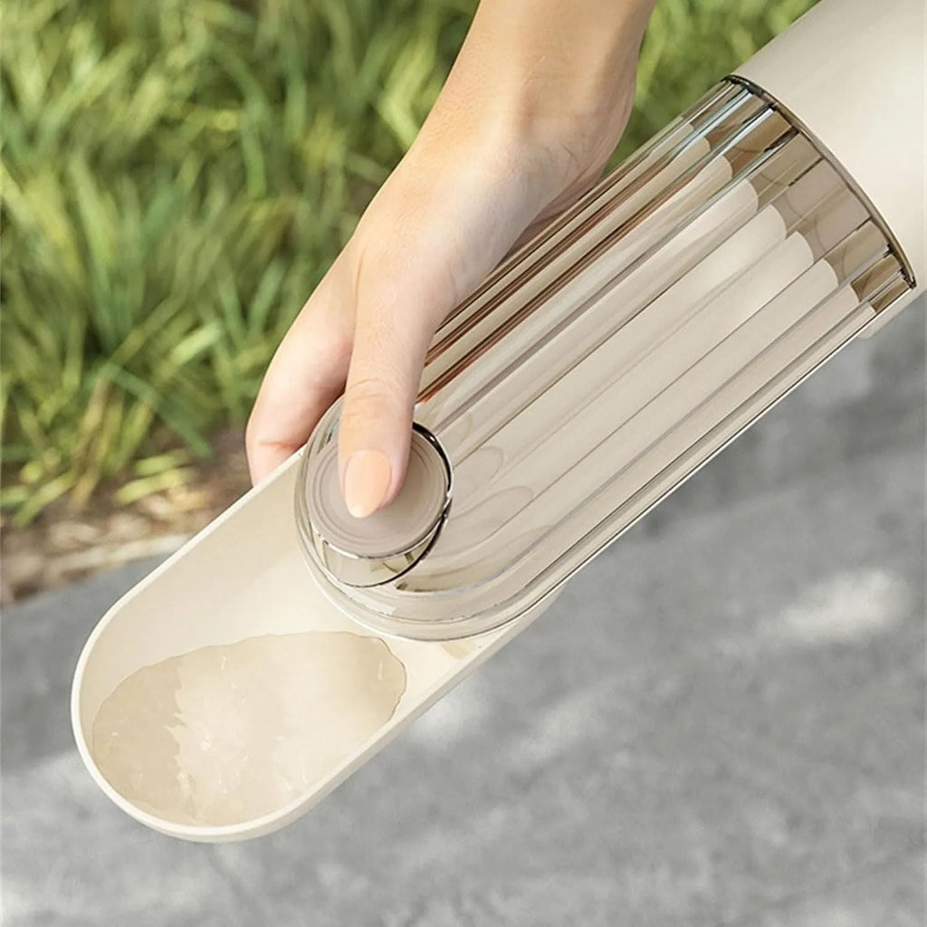 Beige foldable dog water bottle with food container, showing dispenser tray and compact size.