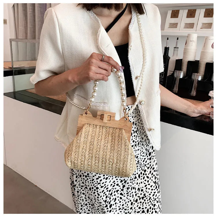 Women's woven straw shoulder bag with pearl chain strap showing interior organiser compartments