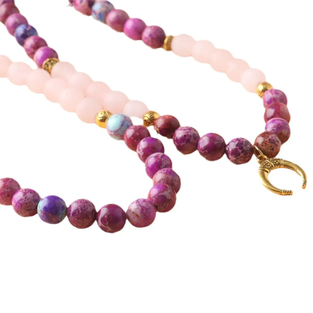 Round pink Emperor Stone pendant on a silver-tone chain, laid flat.