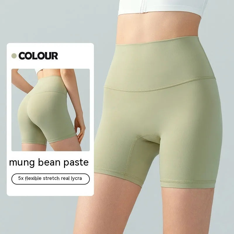 Women's high-waisted Lycra yoga shorts in leaf green, showing anti-exposure construction and short length.