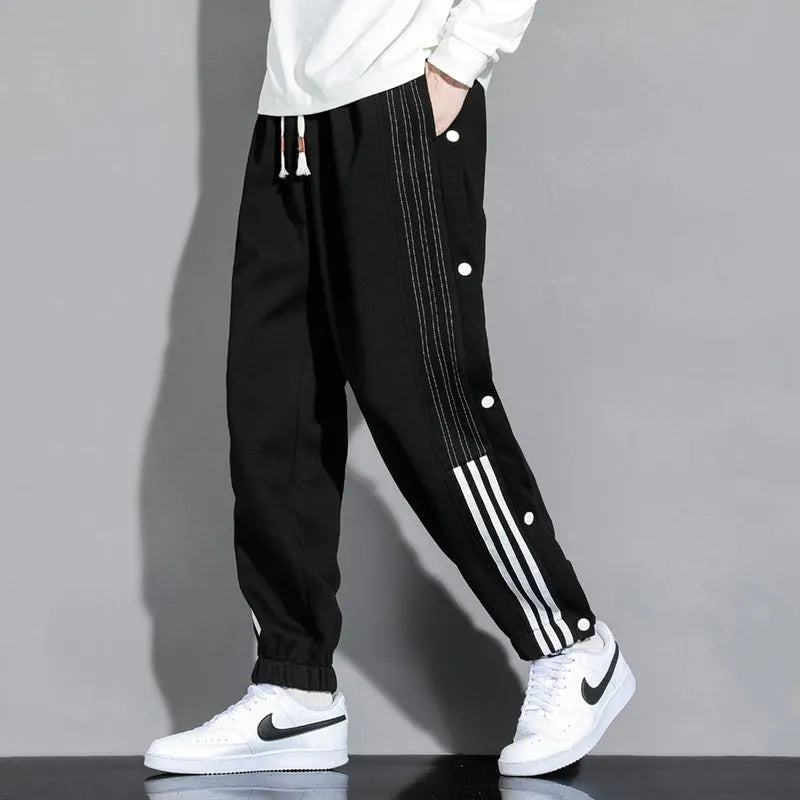 Men's black loose-fit sweatpants with ankle ties and a drawstring high waist on a neutral background.